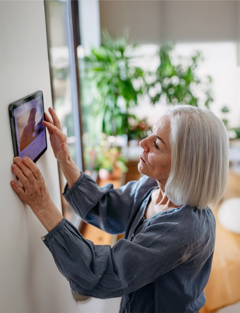 woman adjusting a smart thermostat on the wall for her home heat pump system.